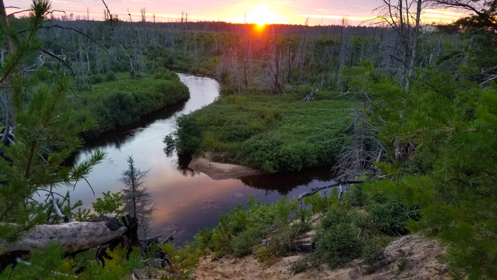 Sunset over sand dunes and river at bottom